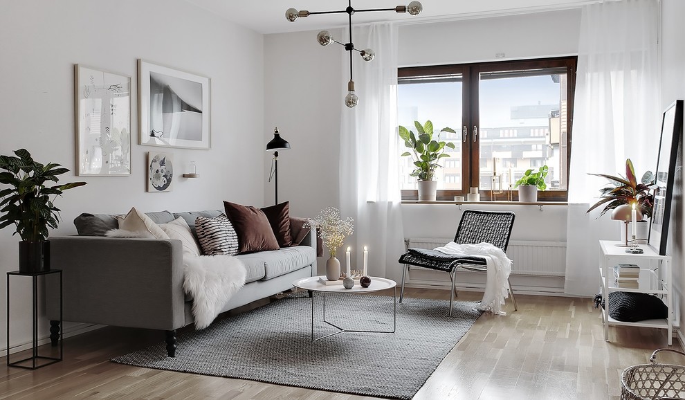 Example of a danish enclosed light wood floor and beige floor living room design in Stockholm with white walls
