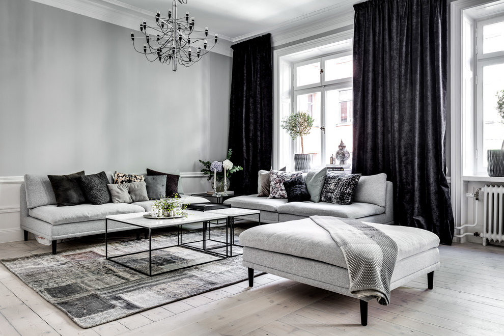 Scandi open plan living room in Stockholm with grey walls, light hardwood flooring and beige floors.