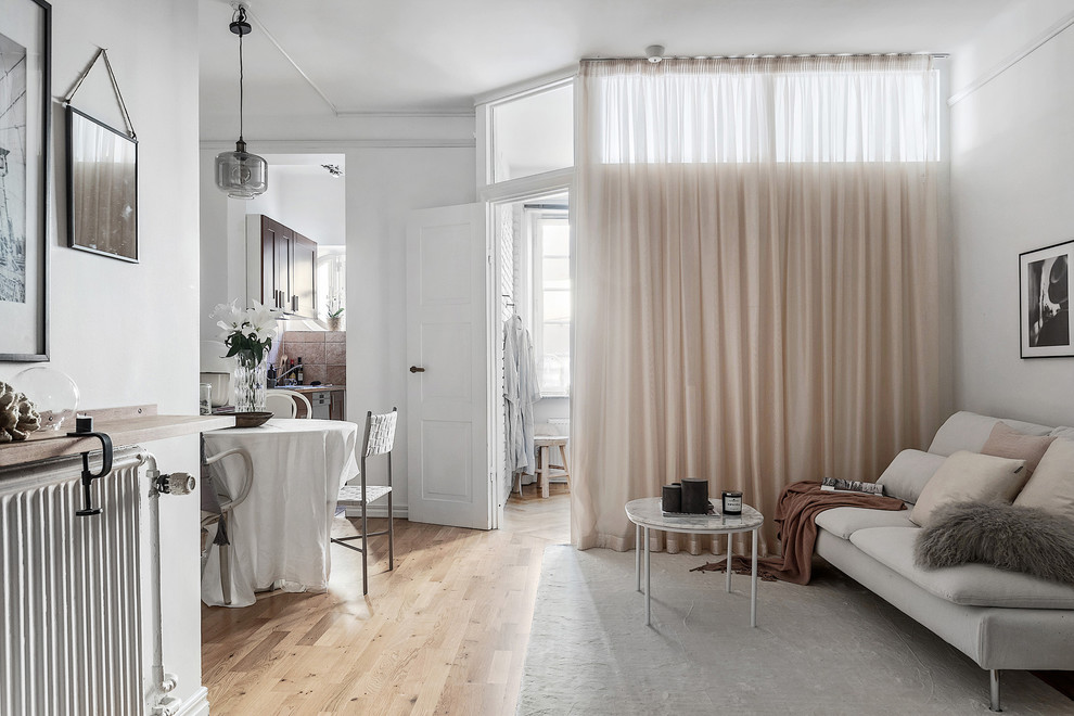Foto di un piccolo soggiorno scandinavo con pareti bianche, pavimento in legno massello medio, nessun camino e nessuna TV