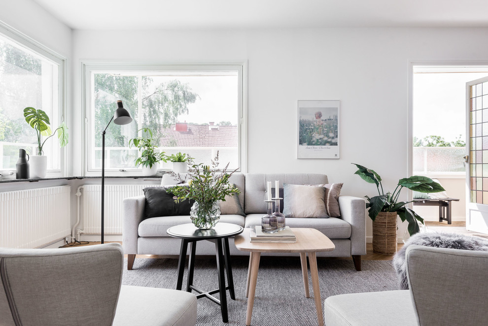Example of a mid-sized danish formal medium tone wood floor living room design in Gothenburg with white walls and no tv
