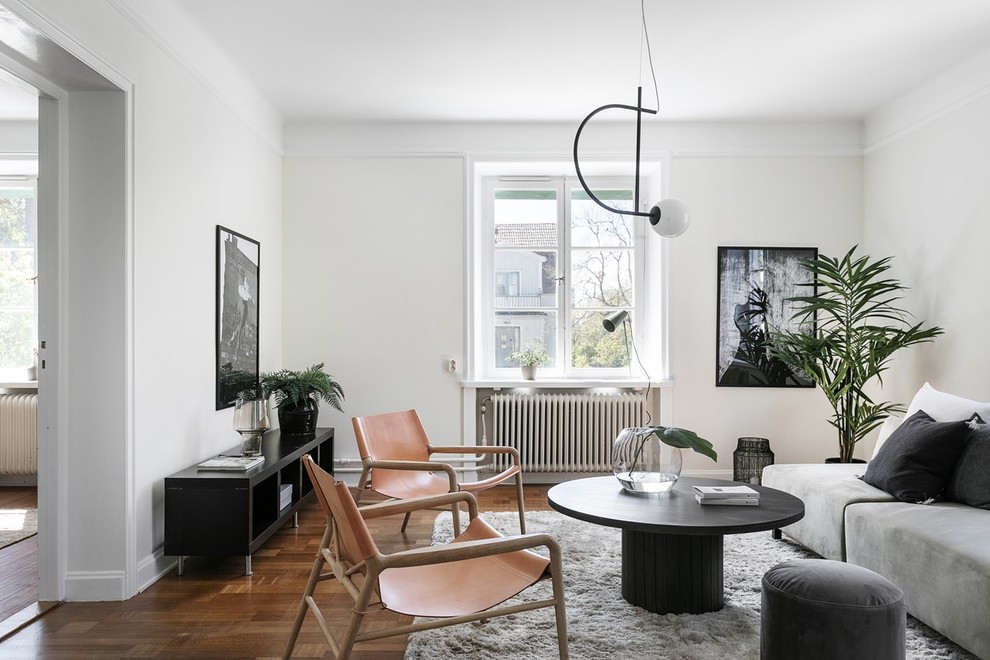 Photo of a scandi enclosed living room in Stockholm with white walls, medium hardwood flooring and brown floors.
