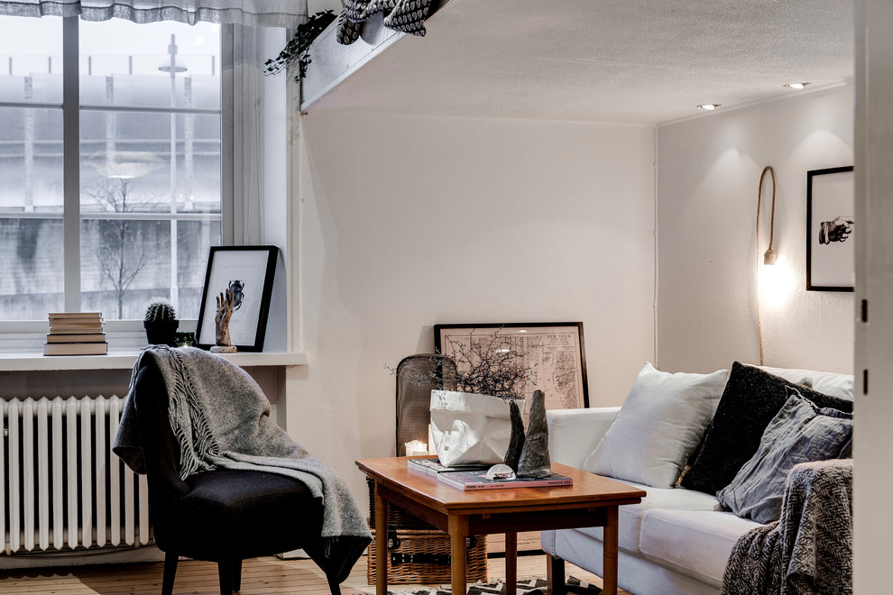 Kleines, Abgetrenntes Skandinavisches Wohnzimmer ohne Kamin mit weißer Wandfarbe, hellem Holzboden und freistehendem TV in Göteborg