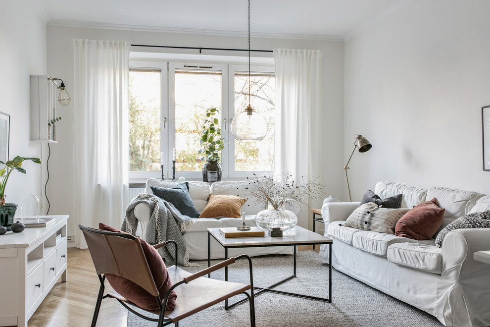 Nordisches Wohnzimmer mit weißer Wandfarbe, braunem Holzboden und braunem Boden in Göteborg