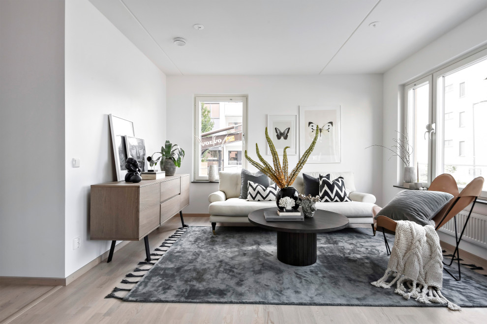 Danish formal light wood floor and beige floor living room photo in Stockholm with white walls, no fireplace and no tv