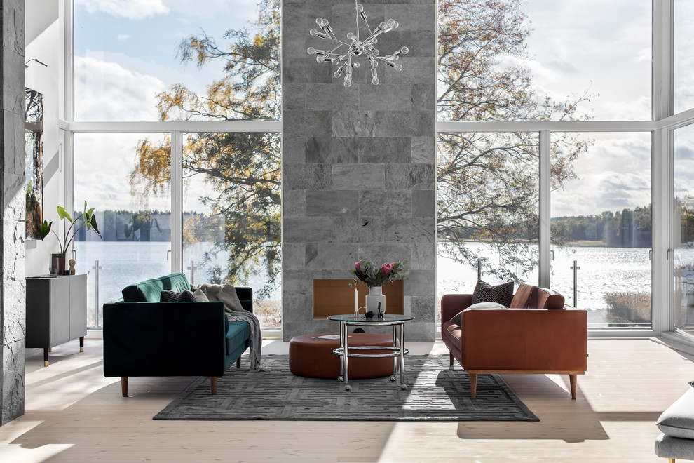 Источник вдохновения для домашнего уюта: большая открытая гостиная комната в скандинавском стиле с светлым паркетным полом, фасадом камина из камня, бежевым полом и серыми стенами