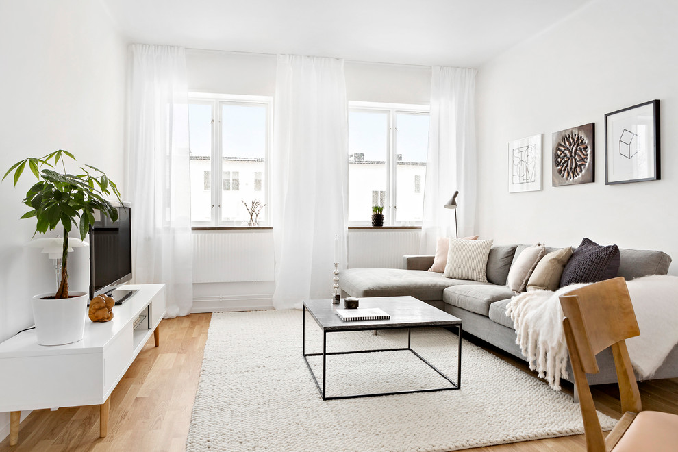 Exempel på ett mellanstort skandinaviskt vardagsrum, med vita väggar, mellanmörkt trägolv och en fristående TV