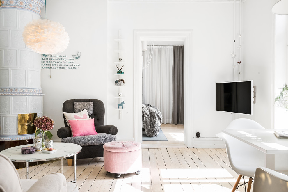 Bild på ett minimalistiskt vardagsrum, med vita väggar, ljust trägolv, en väggmonterad TV och beiget golv
