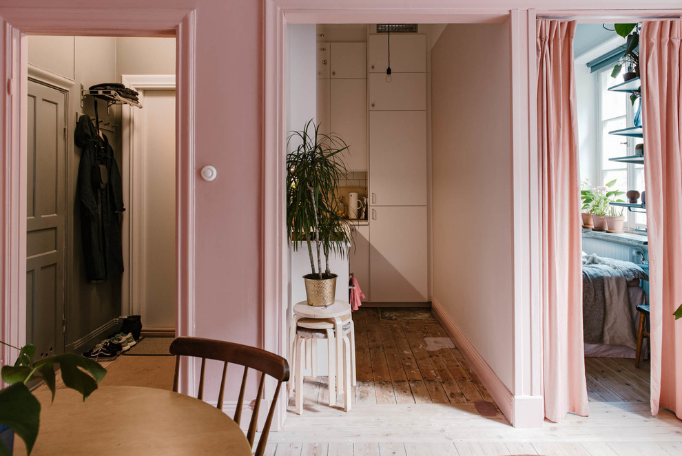 Bild på ett litet minimalistiskt allrum med öppen planlösning, med rosa väggar och mellanmörkt trägolv