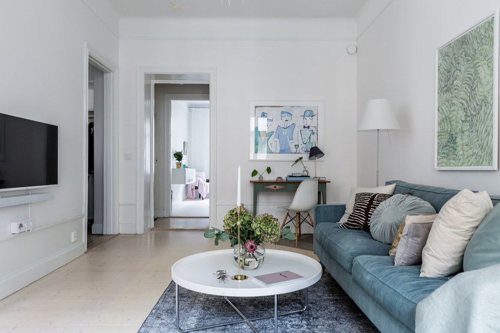 Danish enclosed light wood floor and beige floor living room photo in Stockholm with white walls and a wall-mounted tv