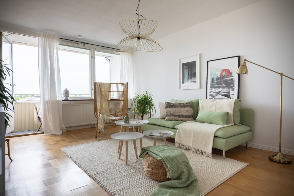 Offenes Nordisches Wohnzimmer ohne Kamin mit weißer Wandfarbe und hellem Holzboden in Stockholm