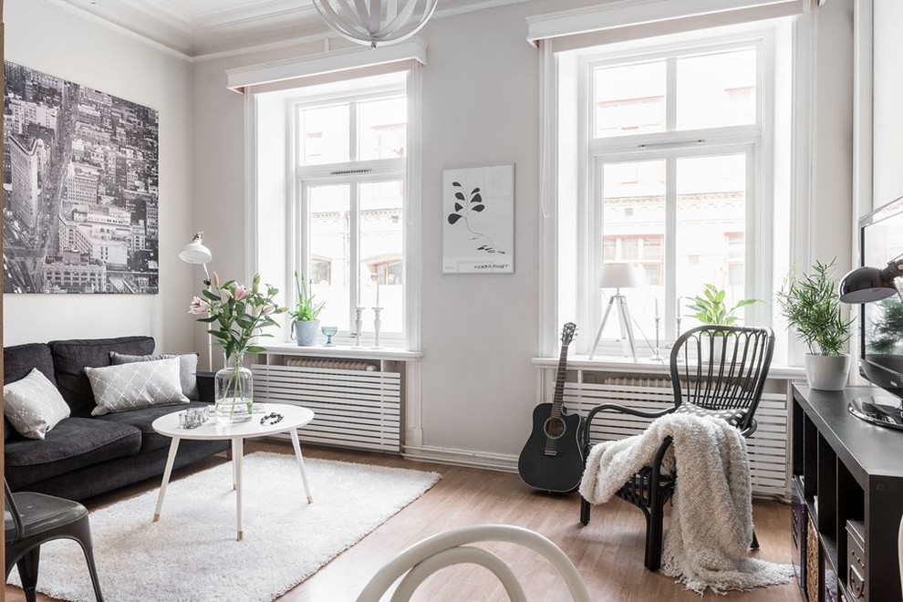 This is an example of a medium sized scandi enclosed living room in Gothenburg with grey walls, light hardwood flooring, no fireplace, a freestanding tv and brown floors.