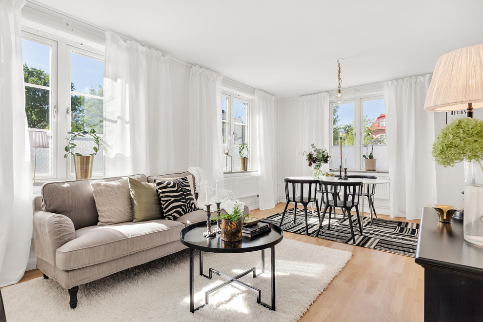 Mittelgroßes, Fernseherloses, Offenes Skandinavisches Wohnzimmer mit weißer Wandfarbe und hellem Holzboden in Stockholm