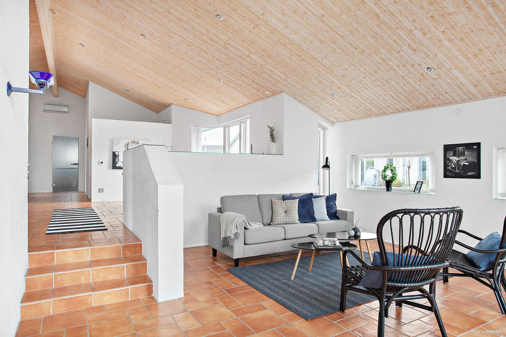 Idée de décoration pour un salon design avec un mur blanc et tomettes au sol.