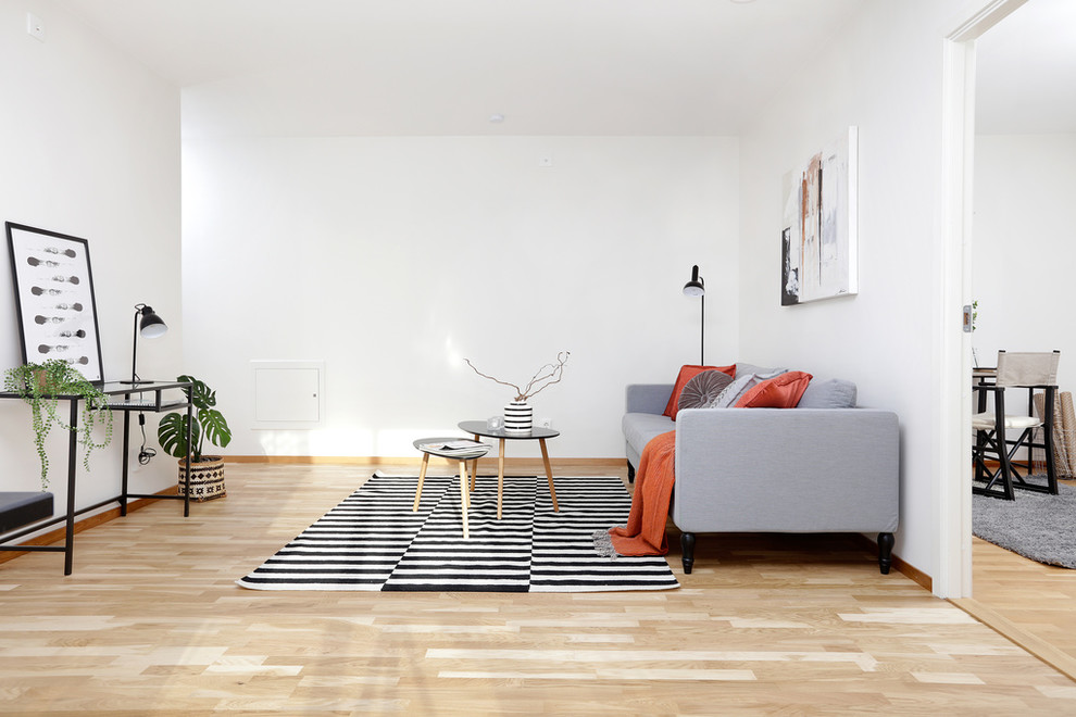 На фото: изолированная гостиная комната в скандинавском стиле с белыми стенами, светлым паркетным полом и бежевым полом без телевизора