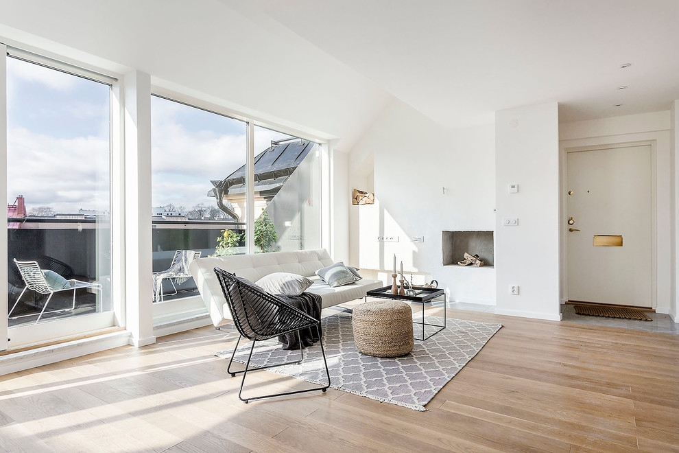 Imagen de salón para visitas abierto escandinavo grande sin televisor con paredes blancas, suelo de madera clara y todas las chimeneas