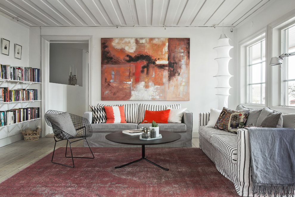 Photo of a large scandi open plan living room in Stockholm with a reading nook, white walls, light hardwood flooring and no tv.