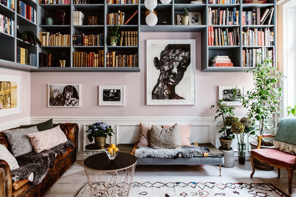 Cette image montre un salon bohème de taille moyenne et fermé avec une bibliothèque ou un coin lecture, un mur rose, parquet clair et un sol beige.