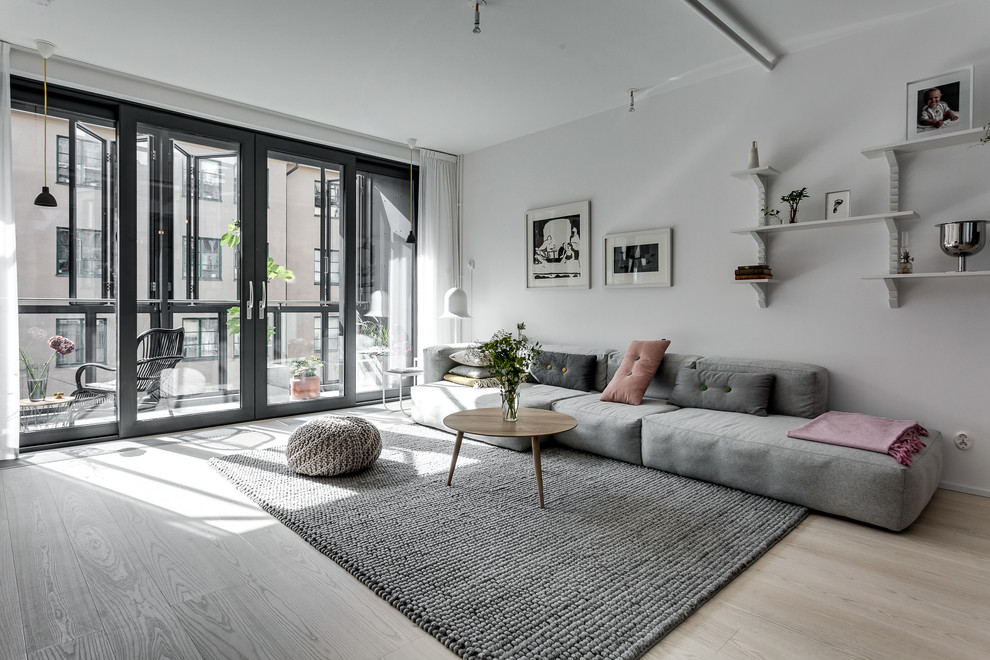 Immagine di un soggiorno minimalista con pareti bianche e parquet chiaro