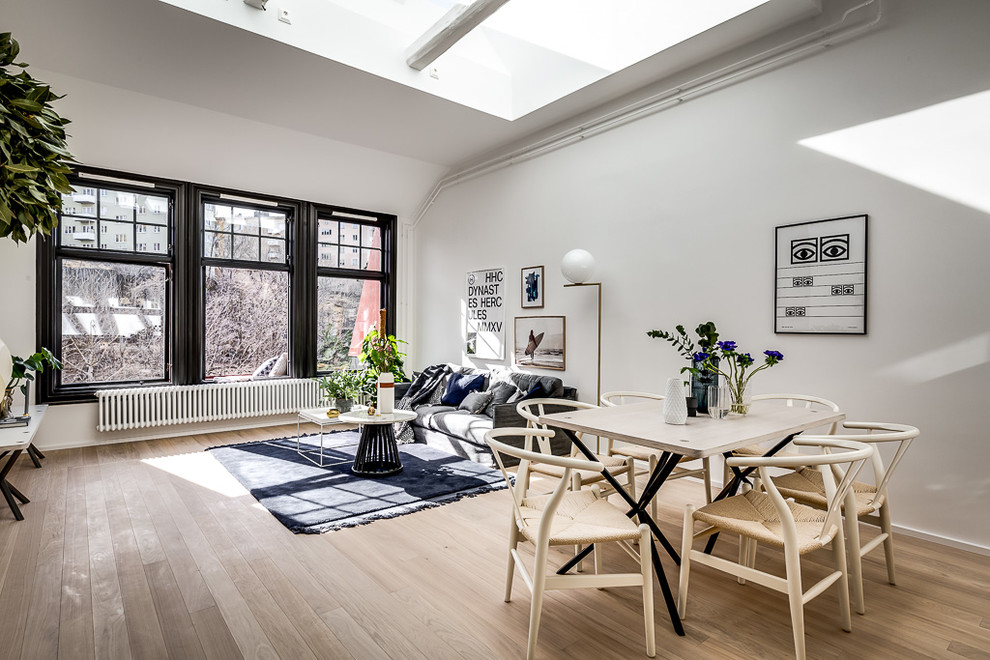 Offenes Nordisches Wohnzimmer mit weißer Wandfarbe, hellem Holzboden und beigem Boden in Stockholm