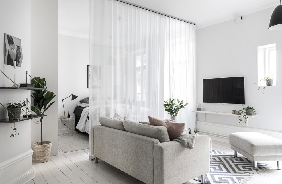 Diseño de salón abierto escandinavo pequeño con paredes blancas, televisor colgado en la pared, suelo de madera clara y suelo beige