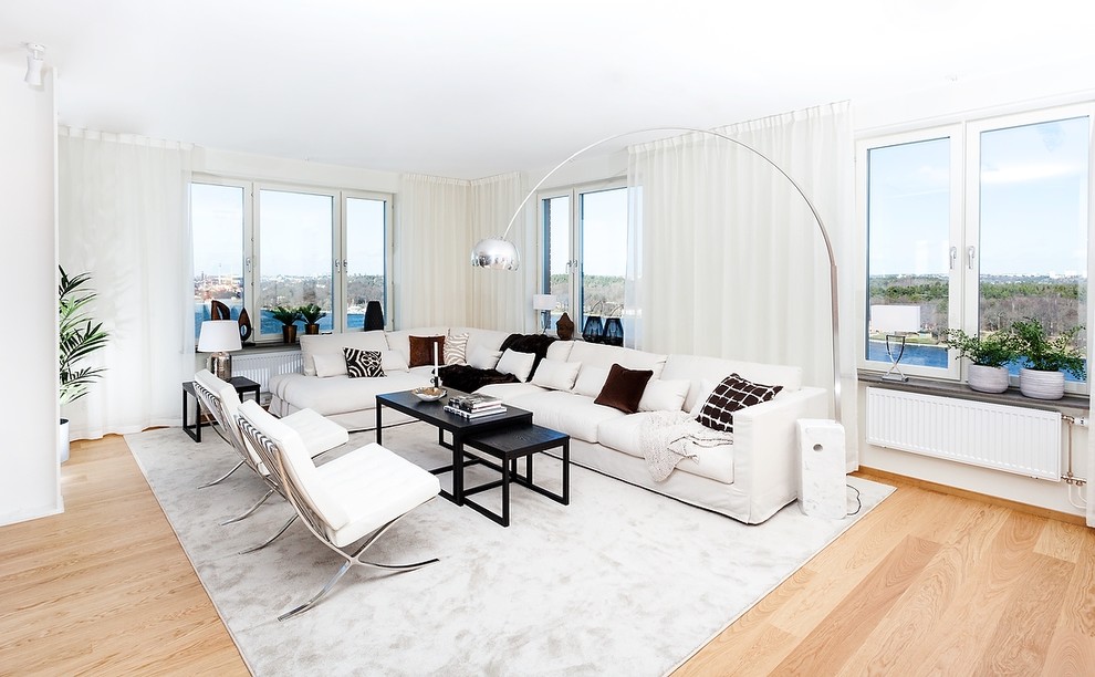 Пример оригинального дизайна: огромная парадная, открытая гостиная комната в современном стиле с белыми стенами, светлым паркетным полом и коричневым полом без телевизора