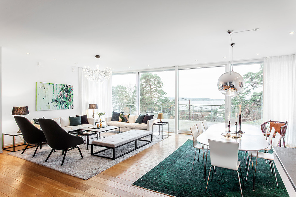 Immagine di un grande soggiorno minimal aperto con pareti bianche, pavimento in legno massello medio, nessuna TV e pavimento marrone
