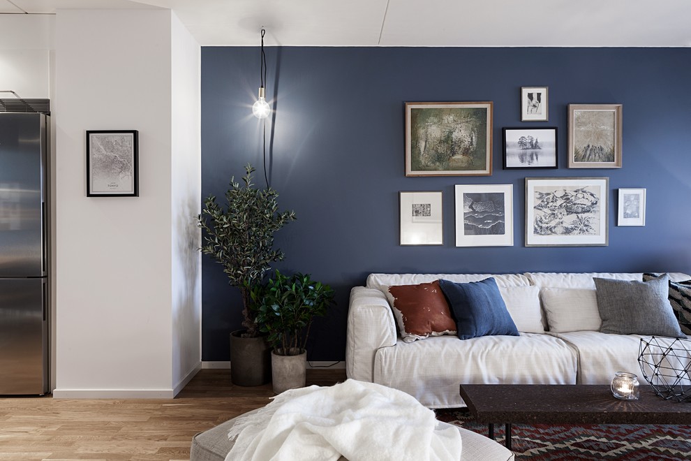 Mittelgroßes, Fernseherloses, Offenes Modernes Wohnzimmer mit blauer Wandfarbe, braunem Holzboden und braunem Boden in Göteborg