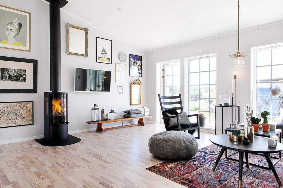 Идея дизайна: большая открытая, парадная гостиная комната в скандинавском стиле с серыми стенами, светлым паркетным полом, печью-буржуйкой и телевизором на стене