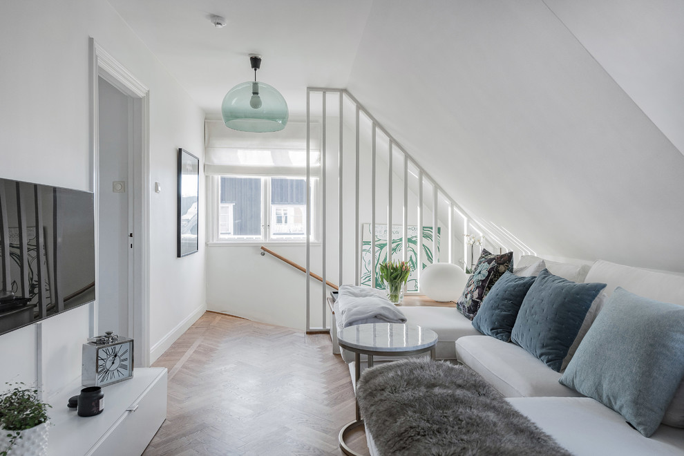 Small danish loft-style medium tone wood floor and brown floor living room photo in Stockholm with white walls and a wall-mounted tv