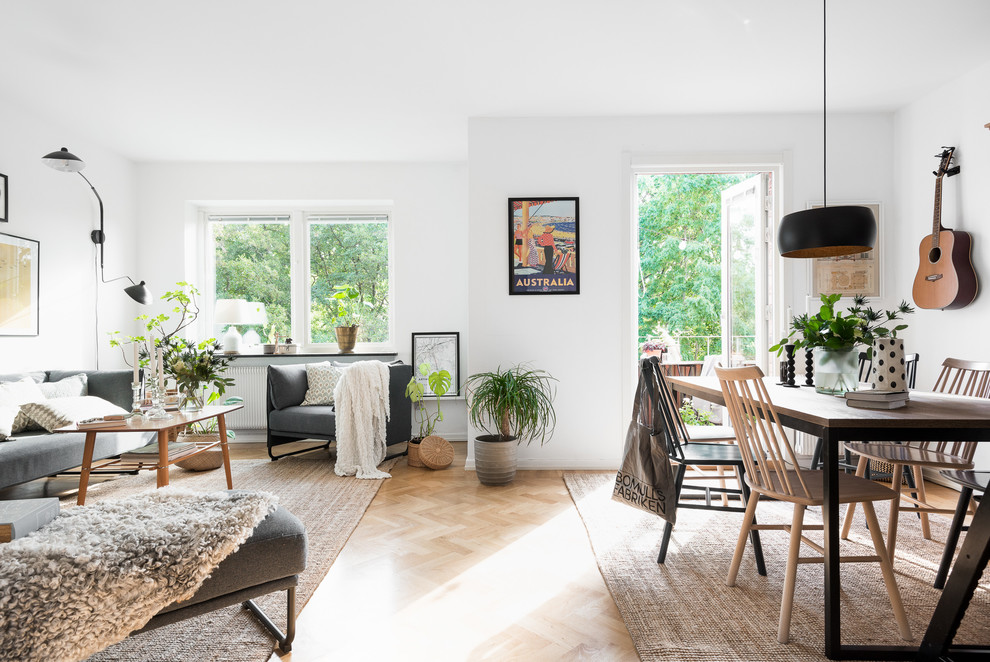 Mittelgroßes, Fernseherloses, Offenes Modernes Wohnzimmer mit weißer Wandfarbe, braunem Holzboden, Eckkamin und Kaminumrandung aus Beton in Göteborg