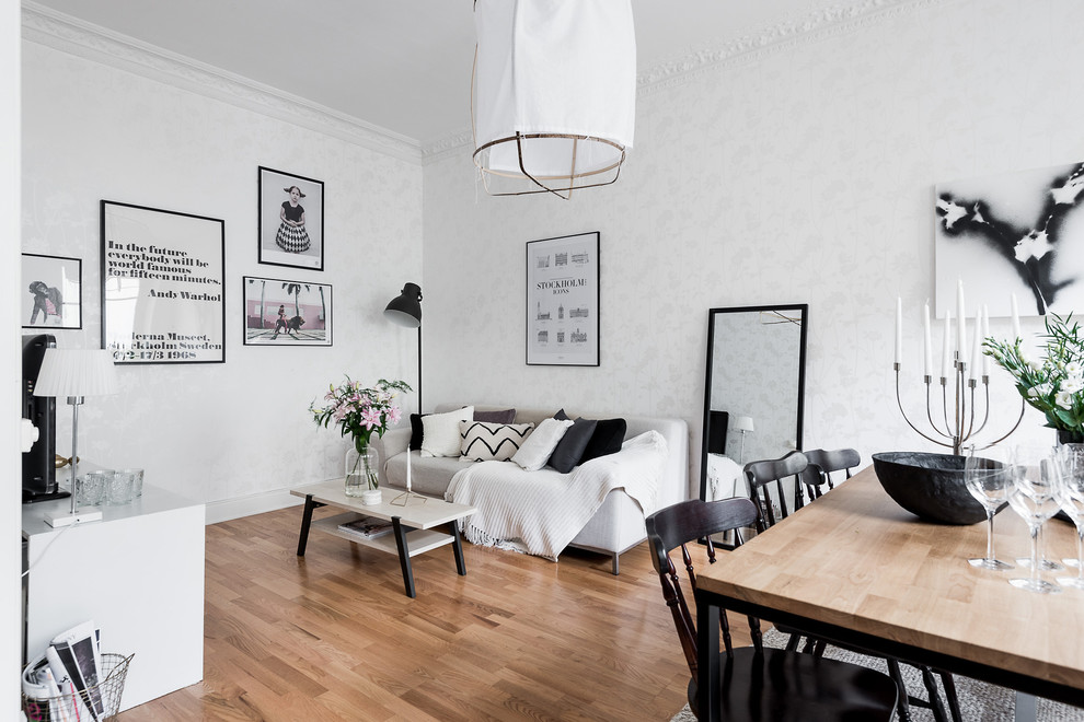 This is an example of a medium sized scandi open plan living room in Gothenburg with white walls and medium hardwood flooring.