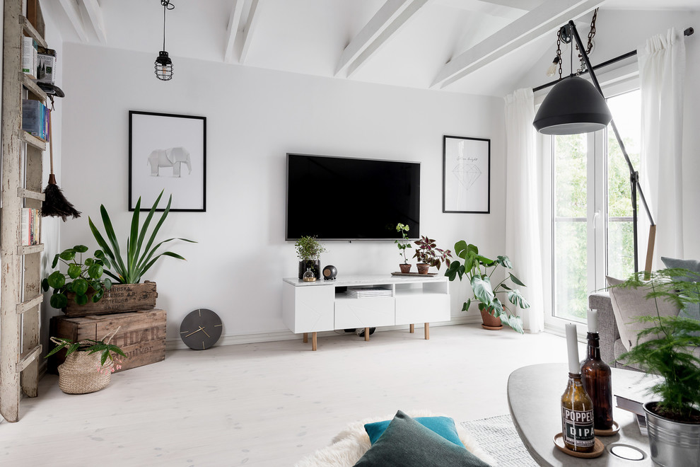 Bild på ett mellanstort nordiskt loftrum, med vita väggar, ljust trägolv och en väggmonterad TV