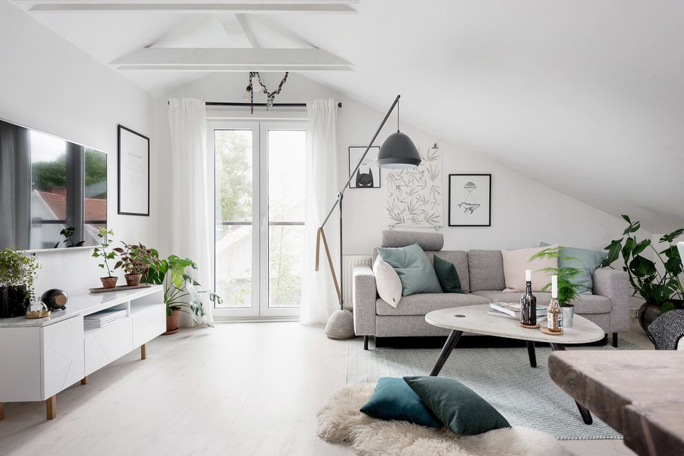 Aménagement d'un salon mansardé ou avec mezzanine scandinave de taille moyenne avec un mur blanc, parquet clair et un téléviseur fixé au mur.