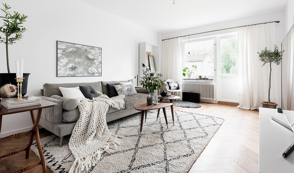 Inspiration for a mid-sized scandinavian open concept medium tone wood floor and brown floor living room remodel in Gothenburg with white walls and a tv stand