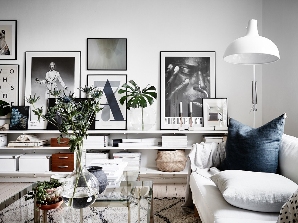Cette image montre un salon nordique avec un mur blanc et parquet clair.