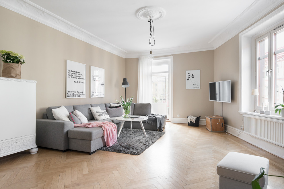 Nordisk inredning av ett mellanstort vardagsrum, med beige väggar, beiget golv, ljust trägolv och en väggmonterad TV