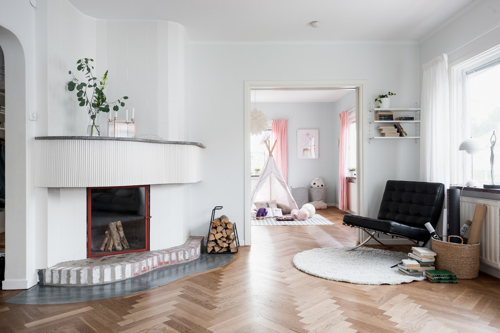 Großes, Fernseherloses, Offenes Skandinavisches Wohnzimmer mit weißer Wandfarbe, braunem Holzboden, Kaminofen und Kaminumrandung aus Stein in Göteborg