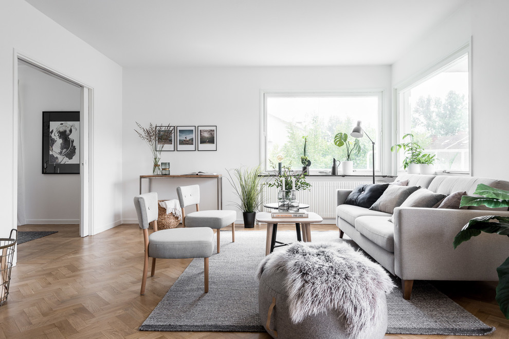 Cette photo montre un salon scandinave fermé et de taille moyenne avec un mur blanc, un sol en bois brun, une salle de réception et éclairage.