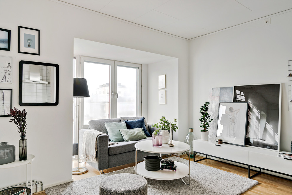 Inspiration för små skandinaviska vardagsrum, med vita väggar och mellanmörkt trägolv