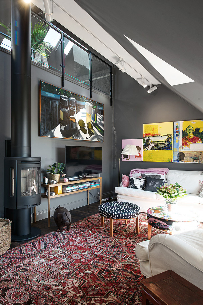 Inredning av ett modernt stort allrum med öppen planlösning, med ett finrum, grå väggar, mörkt trägolv och en fristående TV