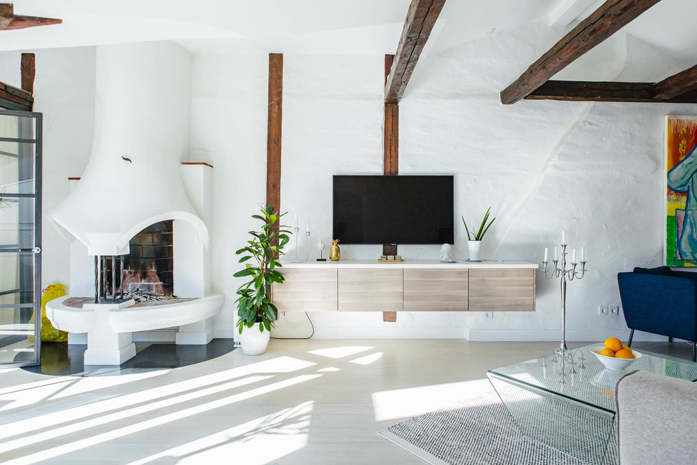 Modelo de salón para visitas abierto nórdico grande con paredes blancas, suelo de madera clara, chimenea de doble cara y televisor colgado en la pared