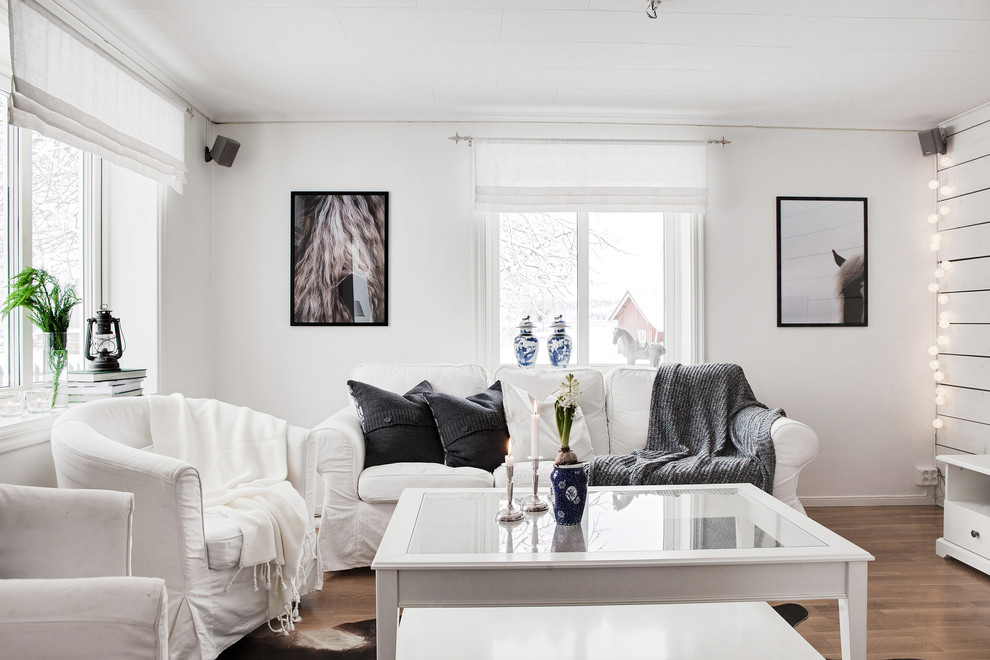 Photo of a scandinavian living room in Gothenburg with white walls, medium hardwood flooring and brown floors.