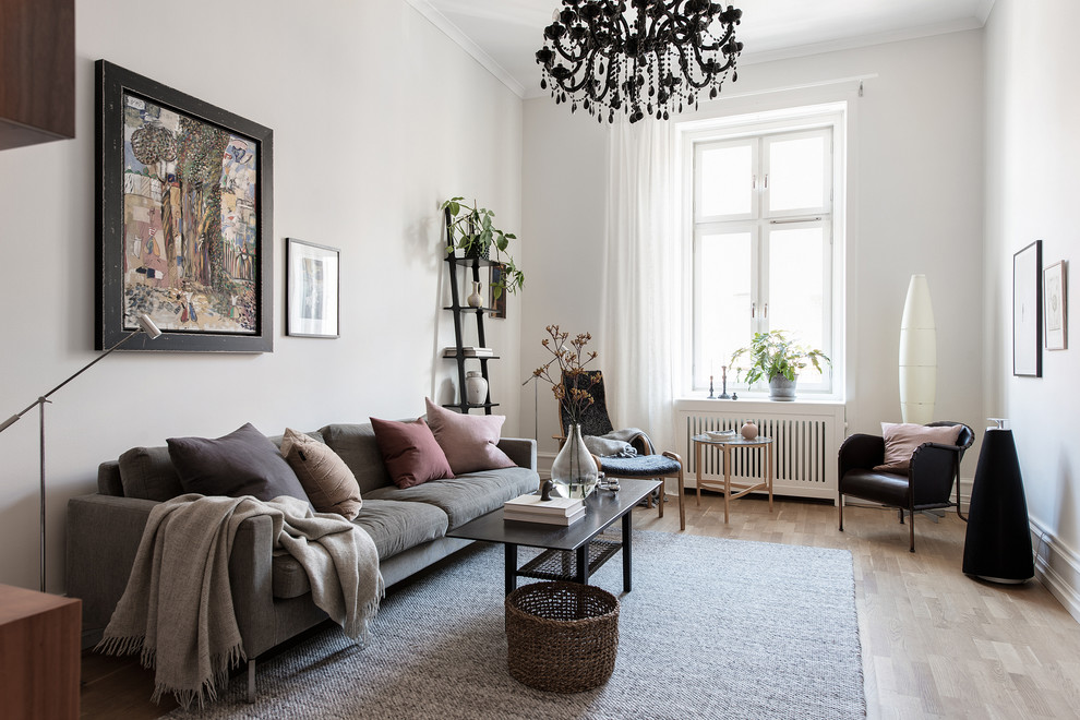 Immagine di un soggiorno scandinavo con libreria, pareti grigie, parquet chiaro, nessun camino e nessuna TV