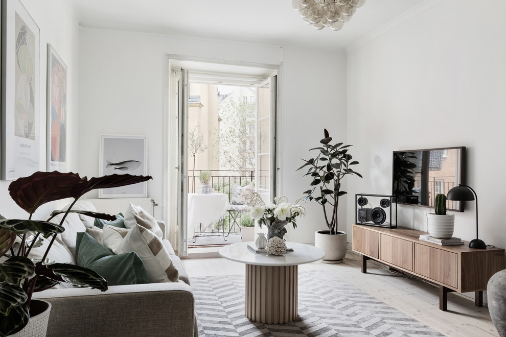 Inspiration för ett minimalistiskt vardagsrum, med vita väggar, ljust trägolv, en väggmonterad TV och beiget golv