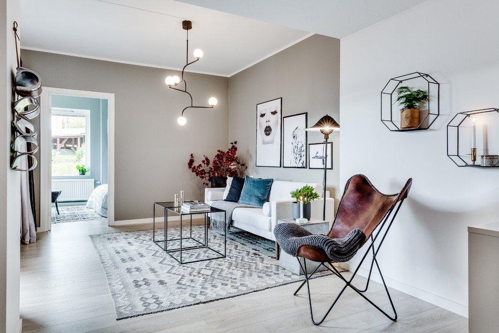 Fernseherloses, Offenes, Mittelgroßes Nordisches Wohnzimmer mit beiger Wandfarbe, hellem Holzboden und grauem Boden in Göteborg