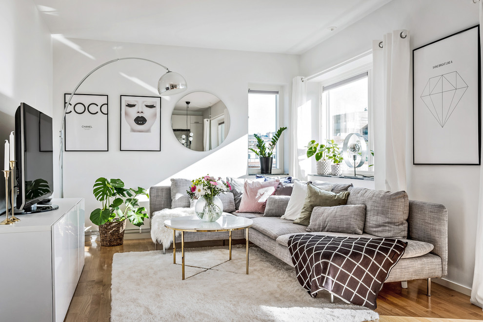 Photo of a medium sized scandi enclosed living room in Gothenburg with white walls, medium hardwood flooring, a freestanding tv and brown floors.