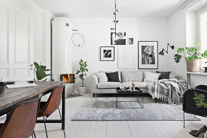 Skandinavisches Wohnzimmer mit weißer Wandfarbe, gebeiztem Holzboden, Eckkamin, gefliester Kaminumrandung und weißem Boden in Stockholm