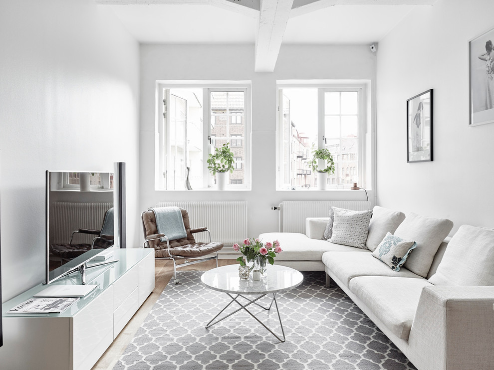 Immagine di un soggiorno scandinavo chiuso e di medie dimensioni con pareti bianche, parquet chiaro, TV autoportante, sala formale e nessun camino