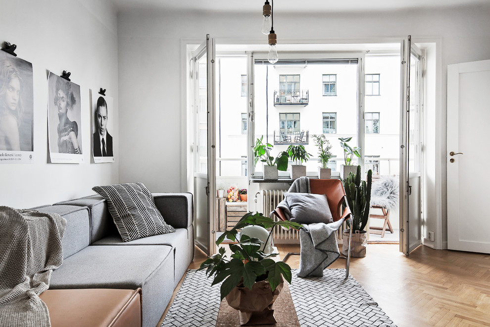 Cette photo montre un salon scandinave de taille moyenne et fermé avec une salle de réception, un mur blanc, un sol en bois brun, aucune cheminée et aucun téléviseur.