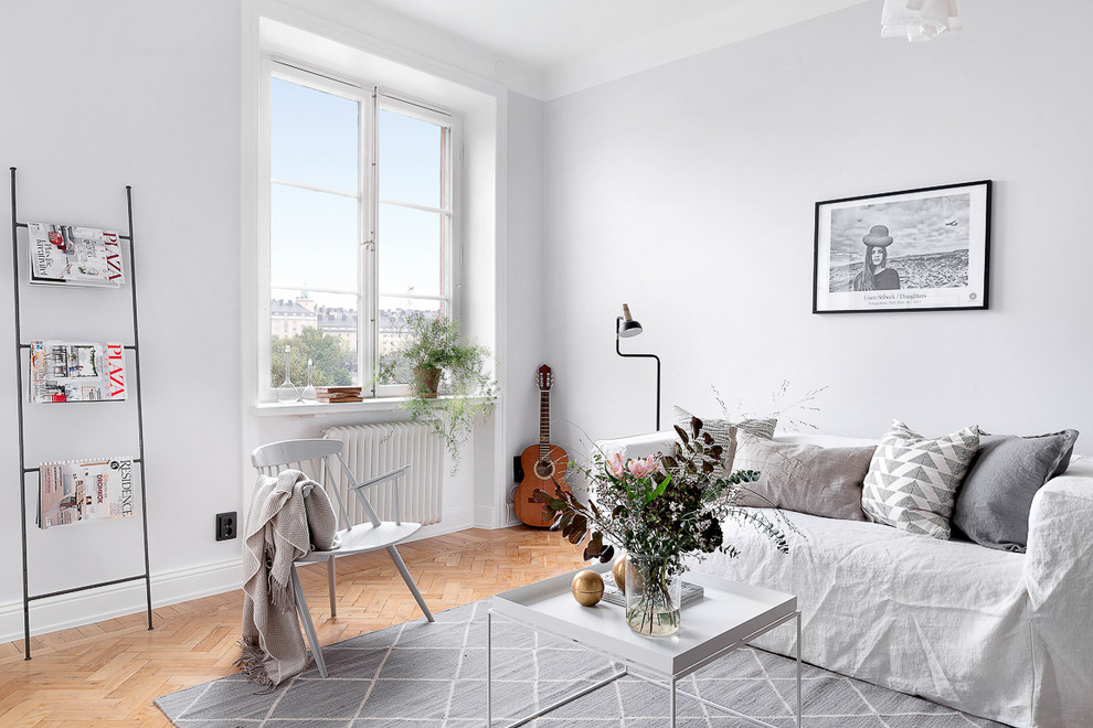 Inredning av ett minimalistiskt vardagsrum, med vita väggar och mellanmörkt trägolv